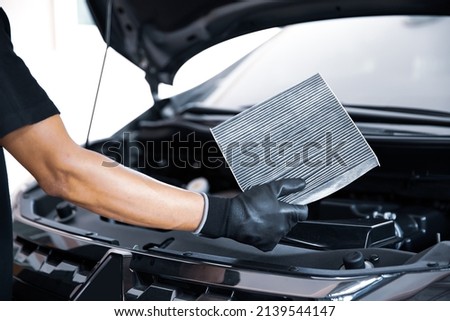 Hand of mechanic holding car air filter old and dirty with dust stains for checking cleaning and replacing new filter. Concept of car care service maintenance. Royalty-Free Stock Photo #2139544147