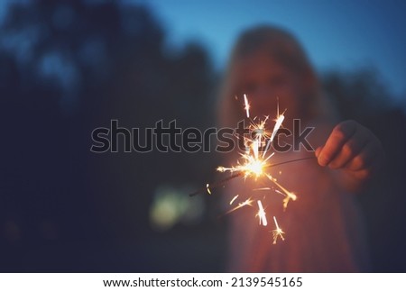 Sparkles are cool. Shot of a unrecognizable little girl playing with a sparkler at night time outside in nature. Royalty-Free Stock Photo #2139545165