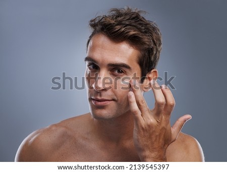 Even men like to be soft..... Studio shot of a handsome young man applying cream to his face. Royalty-Free Stock Photo #2139545397