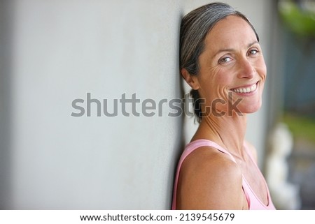 Happiness is an inside job. Portrait of an attractive mature woman in gymwear leaning against a gray wall. Royalty-Free Stock Photo #2139545679