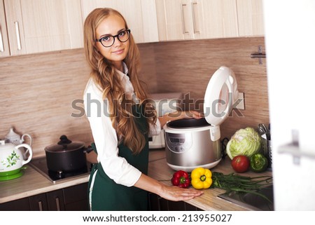 beautiful girl in the kitchen with crockpot slo-cooker Royalty-Free Stock Photo #213955027