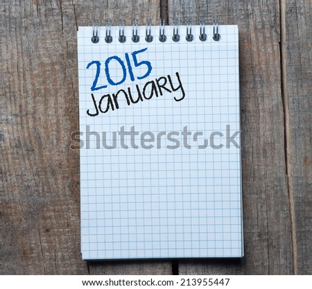 2015 year sign and January month symbol. Page of Notepad and its page on wood background with 2015 year sign and January month symbol.
