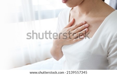Young woman putting her hand on her chest. Having a pain in chest, Gastroesophageal Reflux Disease  have frequent belching. Healthcare medical concept.  Royalty-Free Stock Photo #2139557345
