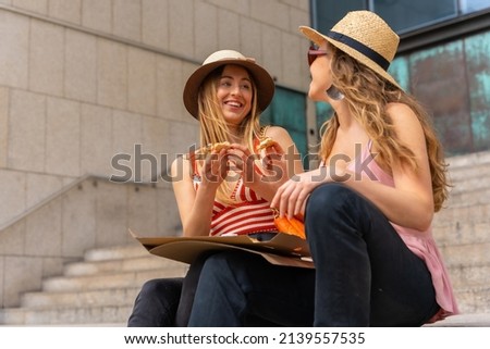 Female friends eating pizza in the city enjoying vacations, smiling young tourists eating the pizza