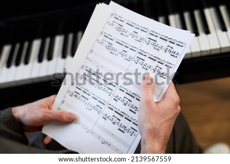 Close-up of musician holding the sheet music and examining them before playing the piano