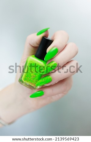 Female hand with long nails and bright neon green nail polish