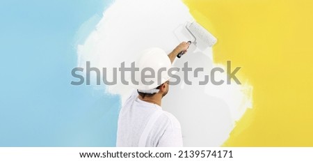 peace and stop the war in ukraine, concept, painter man paint yellow and blue colors of the flag of Ukraine. isolated on white wall