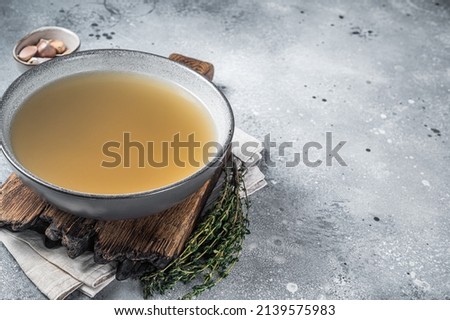 Bone meat chicken broth in a plate. Gray background. Top view. Copy space.