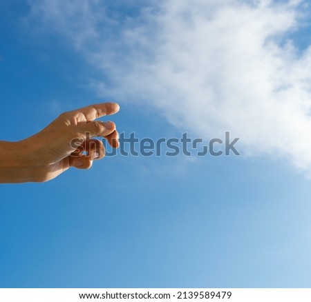 A woman's hand against the blue sky and a white cloud points up. Hand gesture as a move forward to victory. Copy space for text.