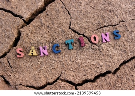 Wooden letters with the inscription: "Sanctions" on the cracked earth.The concept of the destruction of the state. Sanctions against the Russian Federation.