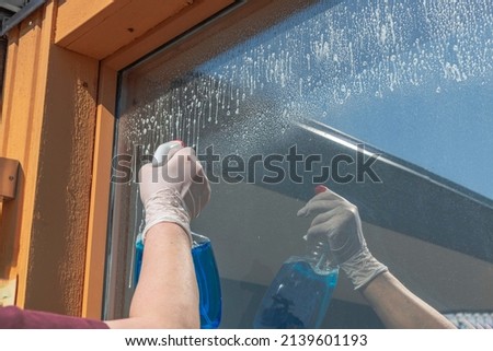 Beautiful view of woman cleaning an outside window in house. Sweden.