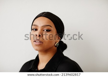 Minimal portrait of beautiful black woman looking at camera while standing against neutral background, copy space