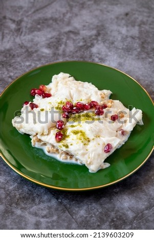 Gullac dessert on dark background. Traditional Ramadan dessert. Güllaç dessert decorated with pistachio and pomegranate. Turkish cuisine delicacies. Close up Royalty-Free Stock Photo #2139603209