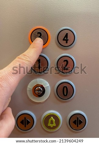Man's hand pressing the button to go up to the third floor of an elevator. Close shot of an orange elevator and a finger pressing the button that makes the elevator go up to his floor.