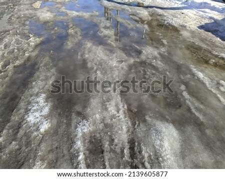 melted snow in early spring and the reflection of poles with wires in a puddle