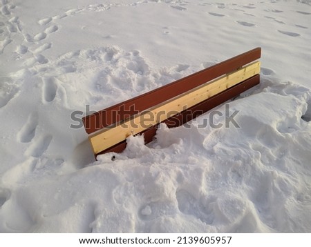 wooden bench almost completely covered with snow