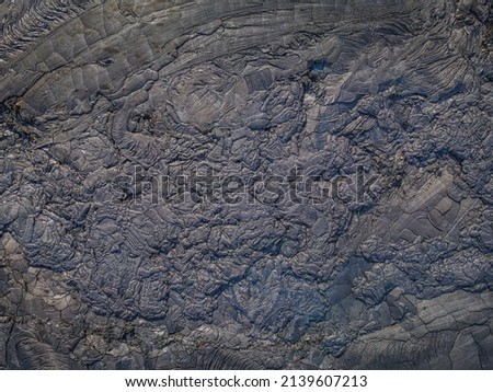 Lava field from above. Cooled lava flow with structures in dark color. Patterns of deflected and broken rocks of flowed lava. Different shades of gray. wavy jagged, fractured patterns of cold magma Royalty-Free Stock Photo #2139607213