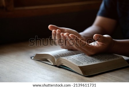 Hands together in prayer to God along with the bible In the Christian concept of faith, spirituality and religion, men pray in the Bible. prayer bible Royalty-Free Stock Photo #2139611731