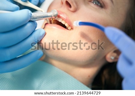 Dentist performing teeth treatment procedure with dental drill Royalty-Free Stock Photo #2139644729