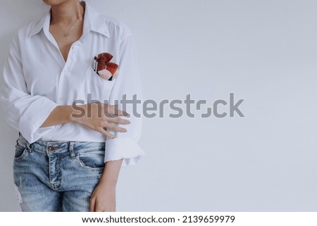 Set of brushes for make-up in white shirt pocket of stylish young girl, studio shot isolated on white background with copy space