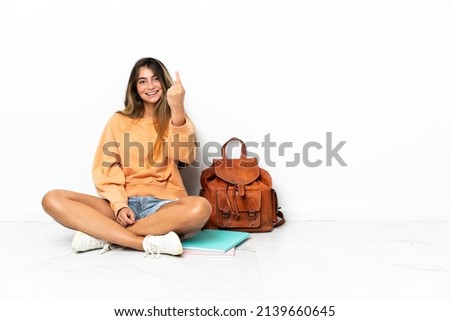 Young student woman sitting on the floor with a laptop isolated on white background doing coming gesture