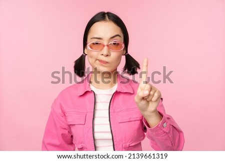 Image of serious, stylish asian girl in sunglasses, showing stop, prohibit gesture, taboo sign, saying no, standing over pink background Royalty-Free Stock Photo #2139661319
