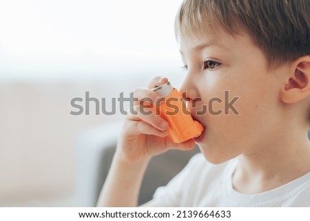 Little boy inhales medicine through an asthma inhaler. Royalty-Free Stock Photo #2139664633