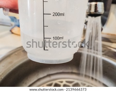 A man pours 100 milliliters of water from the tap at home