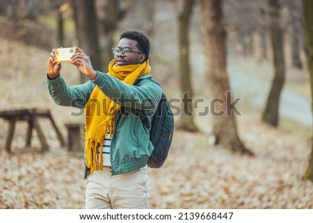 A cheerful African-American enjoys taking selfies. Travel alone, explore wildlife, stay positive. Camping in the woods, time for adventure and the concept of rest