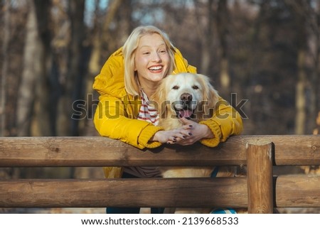 Attractive young woman with Golden Retriever outdoors. Woman in the forest with dog Golden Retriever. Smiling and looking at the camera. Young woman with dog. Pet and woman