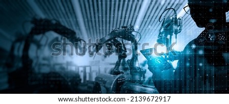 Factory Female Industrial Engineer working with automation robot arms machine in intelligent factory industrial on real time monitoring system software.Digital future manufacture. Royalty-Free Stock Photo #2139672917