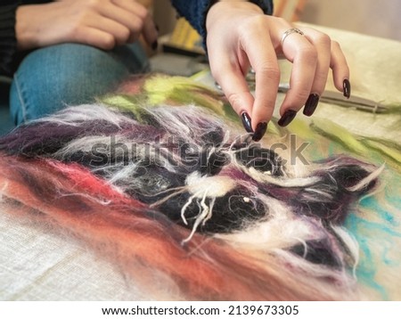 Process of creating a picture of wool. Contemporary art - felting wool, handmade. The painting -depicts the cheerful raccoon. The picture is created from natural wood fibers of different colors.