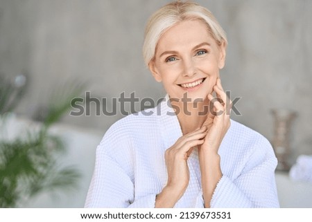 Headshot of happy smiling beautiful middle aged woman wearing bathrobe at spa salon hotel looking at camera touching face. Wellness spa procedures advertising. Skincare concept. Royalty-Free Stock Photo #2139673531