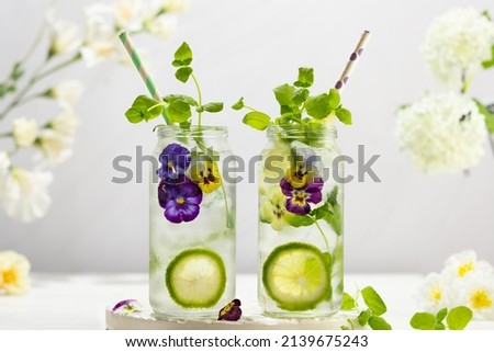 Cold Infused detox water with edible flowers,lime and mint leaves. Refreshing summer drink. Royalty-Free Stock Photo #2139675243