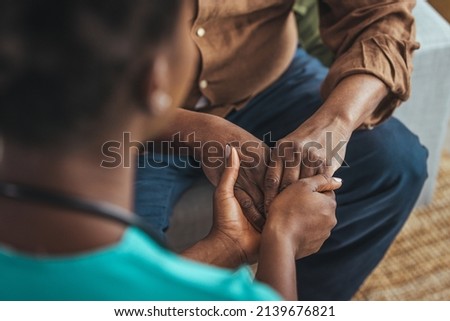 Female healthcare worker holding hands of senior man at care home, focus on hands. Doctor helping old patient with Alzheimer's disease. Female carer holding hands of senior man