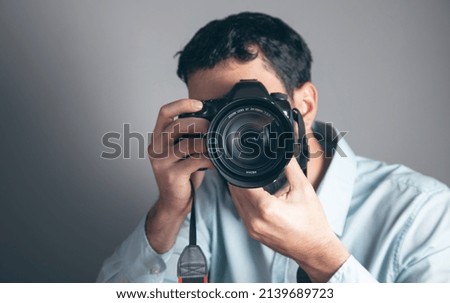 Handsome young man holding digital camera.