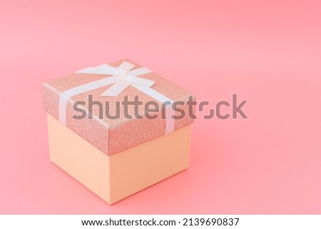 Box with ribbon on a pink background. Copyspace. Festive surprise concept.
