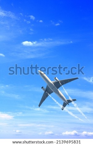 Vertical nature background with aircraft and Jet trailing smoke in the sky. Airplane and condensation trail. Foggy trail jet and plane in blue sky with white clouds. Traveling the world concept Royalty-Free Stock Photo #2139695831