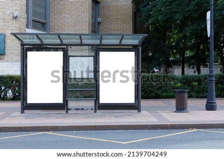 Vertical billboard at a public transport stop. Greened street. Mock-up. Royalty-Free Stock Photo #2139704249