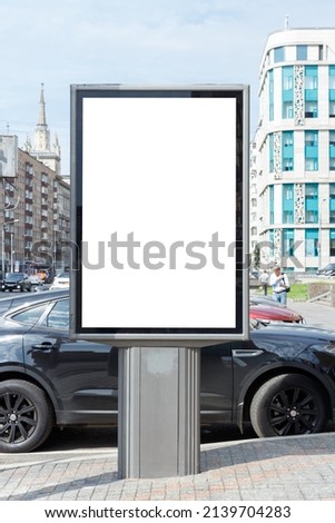 Vertical billboard for advertising and text. Parked cars, city buildings. Mock-up.