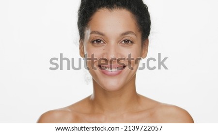 Close-up beauty portrait of young positive African American woman with bare shoulders on white background | Skin care commercial concept Royalty-Free Stock Photo #2139722057