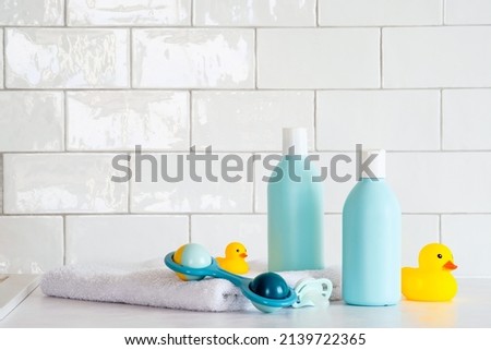 Toiletries baby on tile background. Baby shower gel and shampoo bottle with toy, towel and yellow ducks. Royalty-Free Stock Photo #2139722365