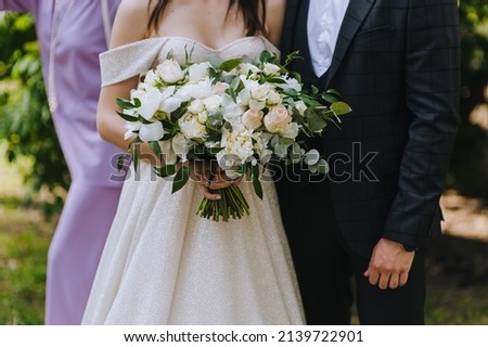 Wedding portrait of a stylish bride and groom with a bouquet of flowers in hand at a ceremony in nature.
