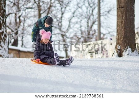 Brother and sister ride on a 
lollipop in the winter