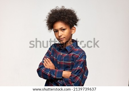Horizontal portrait of bossy displeased and discontent serious African American boy of 13-years-old standing against white background with folded arms. Human emotions and feeling, body language Royalty-Free Stock Photo #2139739637