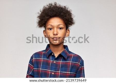 Id picture of handsome adorable dark-skinned boy of 12-years-old standing against cute studio wall with blank copy space for your advertising content, having afro haircut, dressed in stylish shirt