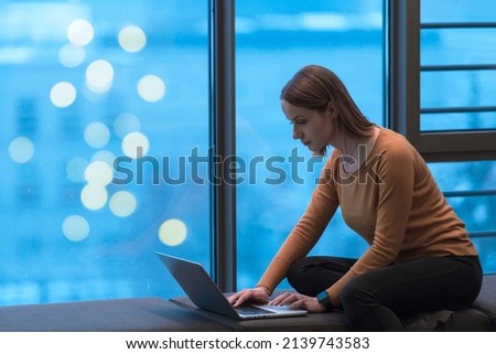 A young woman sitting in a modern space while working on a project on a laptop. Selective focus 