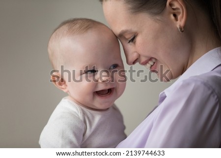 Head shot close up sincere loving millennial mother touching forehead with laughing adorable joyful baby boy girl, expressing candid feelings, enjoying happy motherhood, family devotion concept. Royalty-Free Stock Photo #2139744633