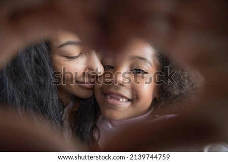 Cheerful Black mom and sweet little daughter kid with tooth gap making hand heart frame, joining fingers, looking at camera, showing symbol of love, gratitude, family, kindness. Close up