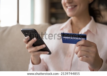 Happy consumer woman shopping online with credit card and mobile phone, paying for virtual purchase on internet, using banking app for payment, transaction. Commerce concept. Cropped shot